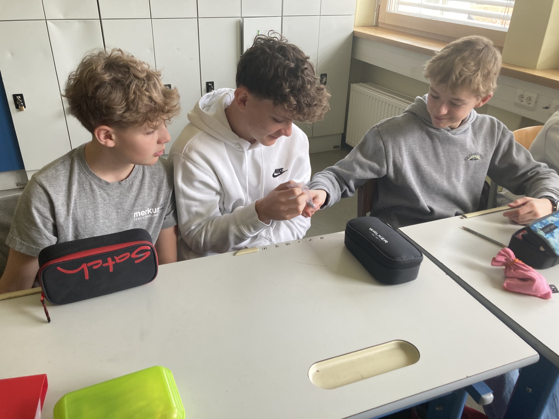 drei Schüler sehen sich gerade eine Materialprobe an 